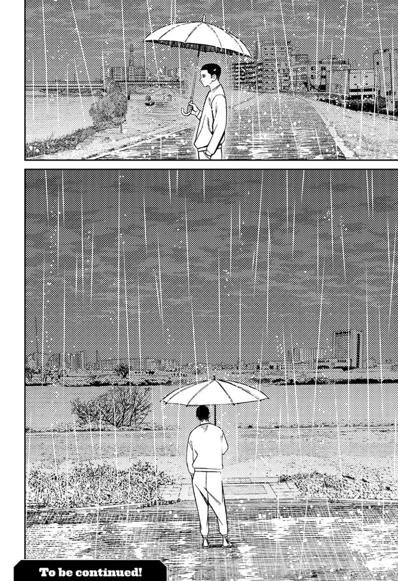 Zuma stands near the river where his brother died. He is holding an umbrella amidst the rain.